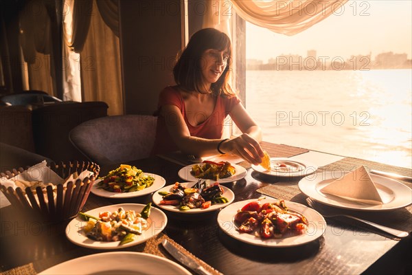 A young tourist having dinner on a boat on the nile a traditional Egyptian meal with the sunset light in the window. Africa