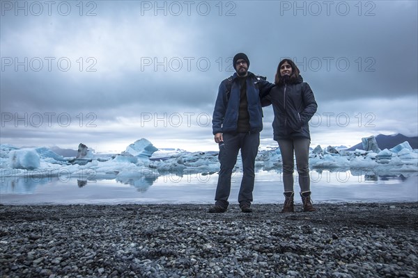 A couple with a backpack looking at the Jokulsarlon Ice Lake in the golden circle of southern Iceland