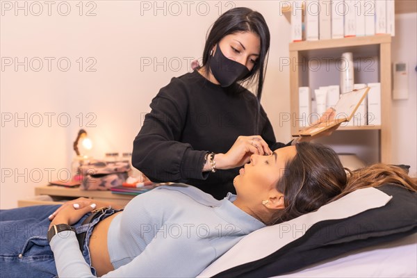 Professional makeup artist attending a client lying on stretcher on a salon