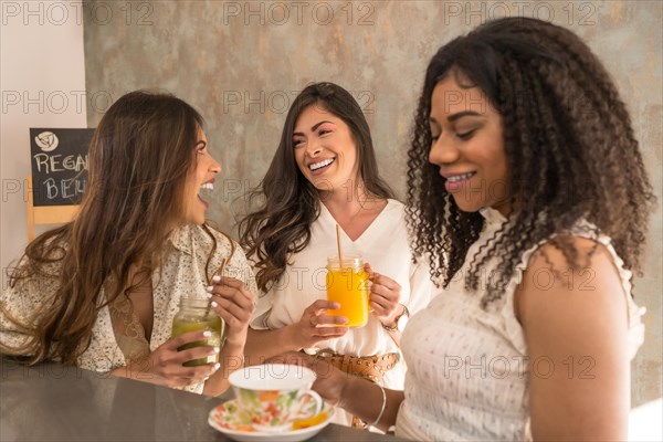 Funny moments of three women laughing and enjoying in a healthy cafeteria