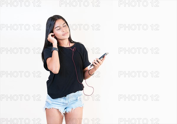 Attractive girl enjoying music with phone isolated. Happy latin gir listening to music with cell phone isolated. Portrait of beautiful girl listening to music with smartphone isolated