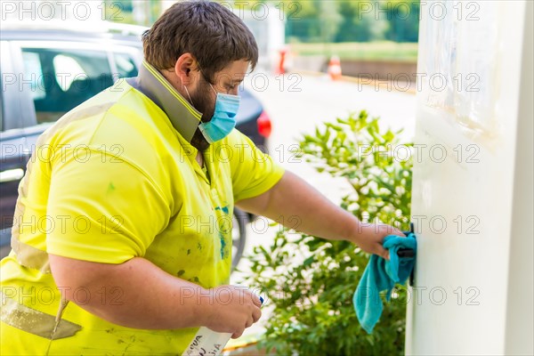 Worker in a recycling factory or clean point and garbage with a face mask and plastic protective screen