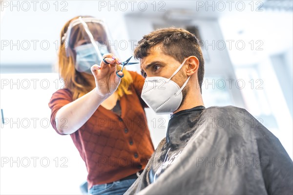 Hairdressers after the Coronavirus pandemic. Hairdresser with face mask and protective screen