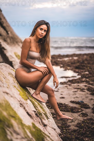 Caucasian brunette with a brown swimsuit at the seaside in the town of Zumaia