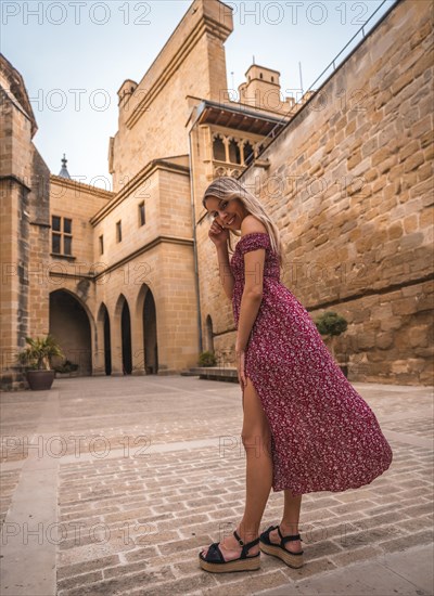 Portrait of a blonde woman in a medieval castle wearing a red dress