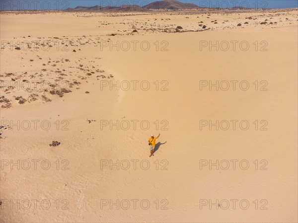 Aerial view of a young man flying the drone in the dunes of Corralejo Park