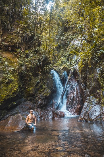 A young man in the impressive waterfall of the Cerro Azul Meambar National Park