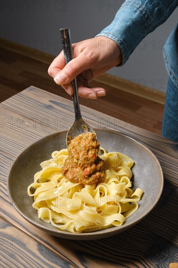 High angle view of unrecognizable woman serve vegetable sauce in plate with pasta