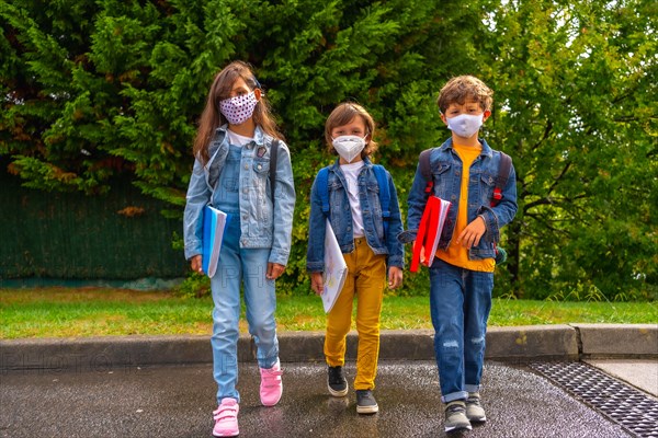 Three brothers with face masks ready to go back to school. New normality