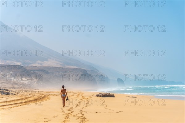 A young woman on the wild beach Cofete of the natural park of Jandia