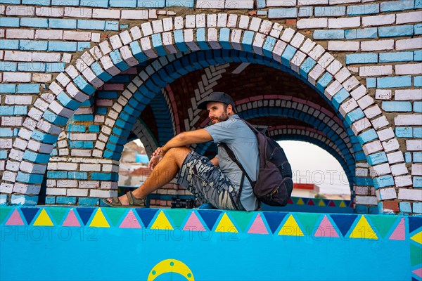 A young tourist sitting on a beautiful terrace of a traditional blue house in a Nubian village along the Nile river and near the city of Aswan. Egypt