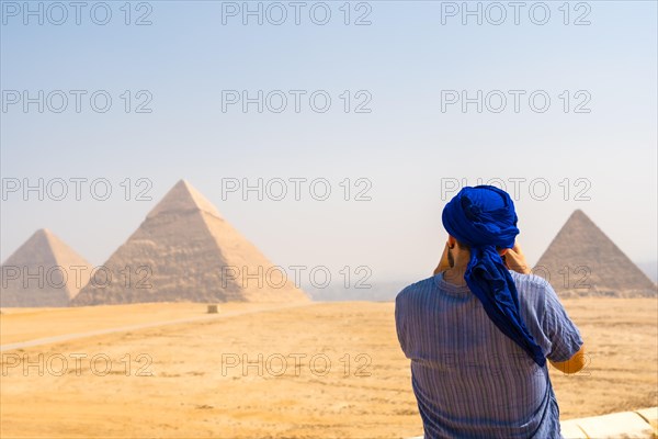 A young tourist wearing blue turban and sunglasses enjoying the Pyramids of Giza