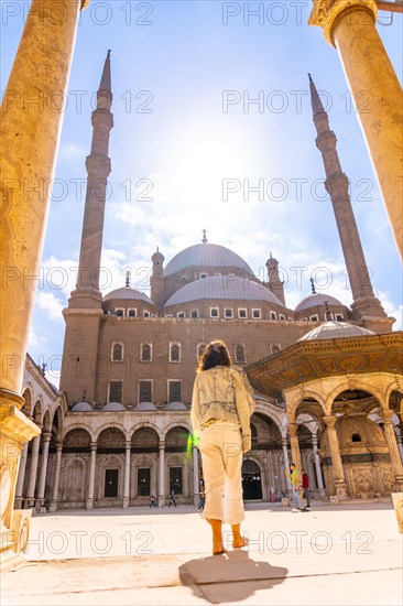 A young tourist walking in the inner courtyard of the Alabaster Mosque and the gigantic pillars in the city of Cairo