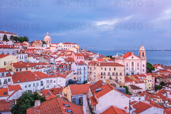 View of Lisbon famous view from Miradouro de Santa Luzia tourist viewpoint over Alfama old city district on sunset with dramatic overcast sky. Lisbon