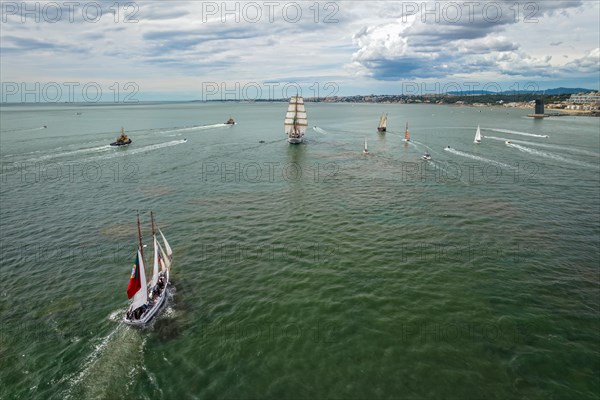 Aerial drone view of tall ships with sails sailing in Tagus river towards the Atlantic ocean in Lisbon