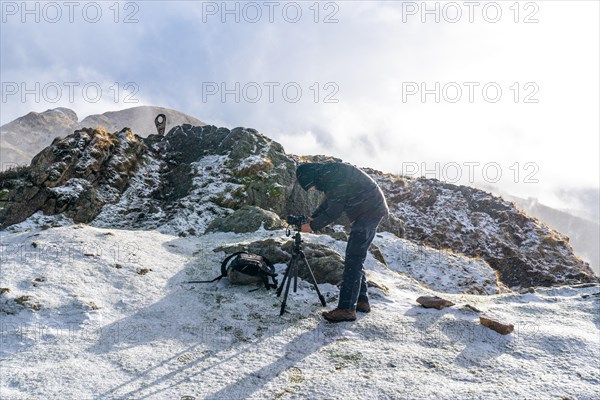 A photographer getting ready in the snowy winter sunset on Mount Penas de Aya in the town of Oiartzun near San Sebastian