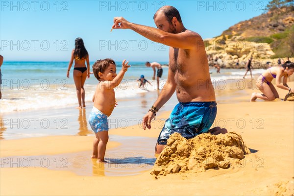 Father playing in the sand with son
