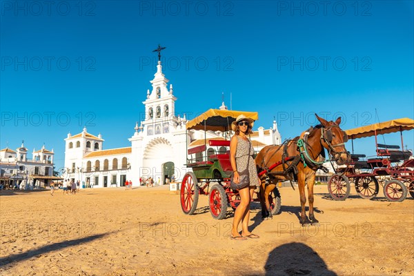 A tourist next to horses and carriages in the Rocio sanctuary in the festival of El Rocio in summer