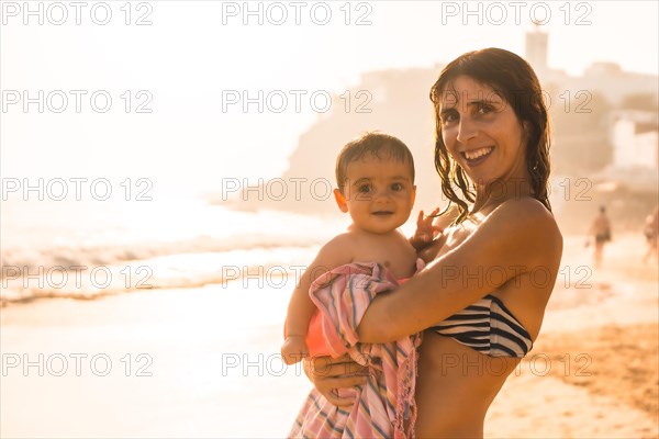 A mother with her baby enjoying a sunset on a beach