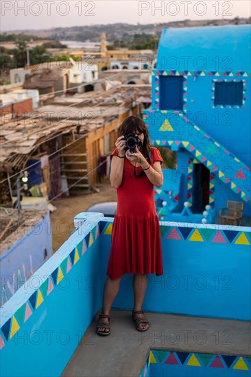 A young woman looking at the village from a beautiful terrace of a traditional blue house in a Nubian village along the Nile river and near Aswan city. Egypt