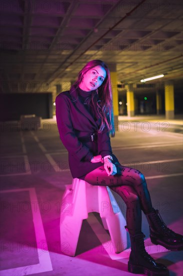 Brunette Caucasian girl sitting in a parking lot underground