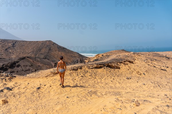 A young woman on a path of the wild beach Cofete of the natural park of Jandia