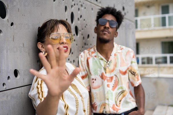 Woman gesturing stop while posing happily with a stylish man in the street