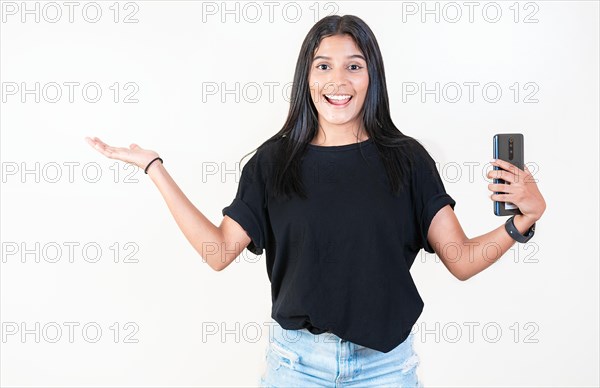 Happy latin girl holding phone and looking at camera. Cheerful young girl holding smartphone and smiling at camera