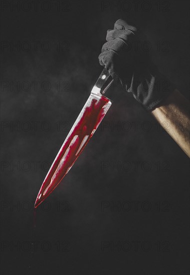 Hand with black glove holding bloodstained knife