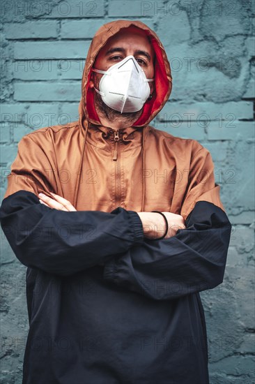 A young Caucasian man wearing a mask and leaning against a wall staring intently. First walks of the uncontrolled Covid-19 pandemic