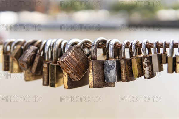 Old rusty padlocks hanging on bridge railing