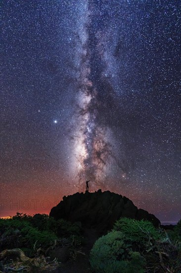 Silhouette of a young man under the stars looking at the lactea way of the Caldera de Taburiente near the Roque de los Muchahos on the island of La Palma