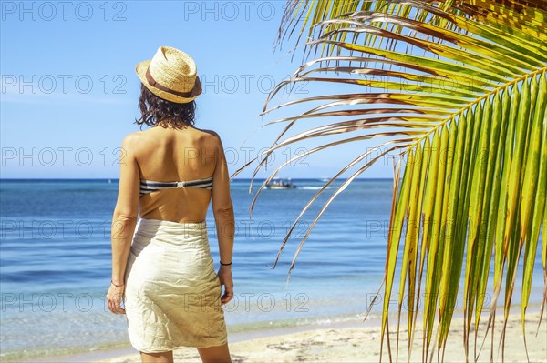 A brunette tourist winged from a palm tree on the West End beach on Roatan Island. Honduras