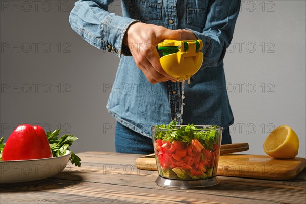 Unrecognizable woman using manual juicer to squeeze lemon into blender bowl