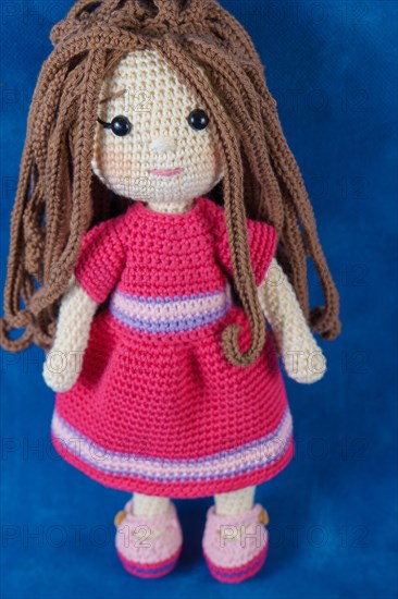 Close-up of a handmade amigurumi doll on a blue background