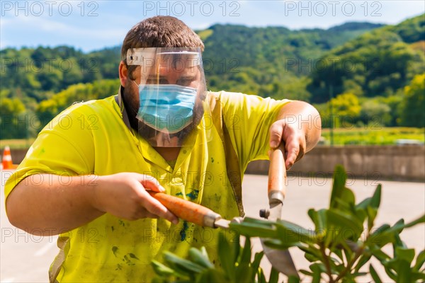 Worker in a recycling factory or clean point and garbage with a face mask and plastic protective screen