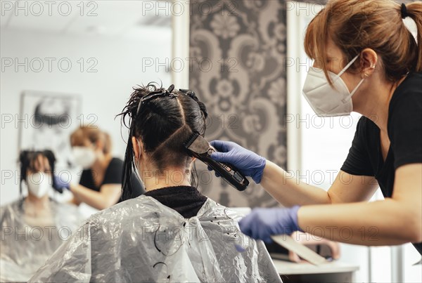 Hairdresser with mask and gloves shaving with razor. Reopening with security measures of Hairdressers in the Covid-19 pandemic