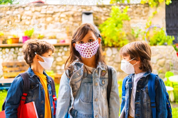 Three brother children with face masks ready for going back to school. New normality