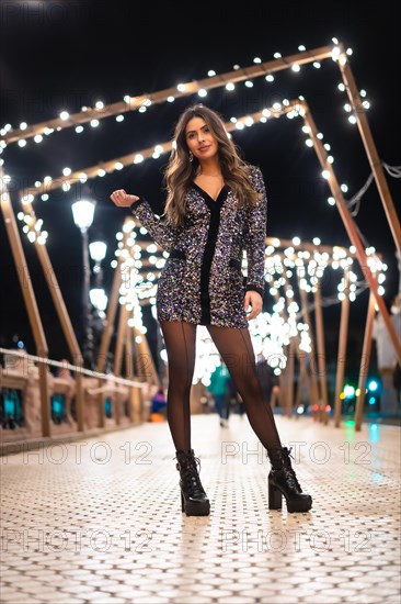 Winter lifestyle at Christmas. Brunette Caucasian girl in a fashionable sequined dress and black high heels