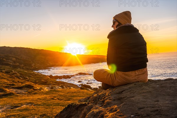 A young woman with a wool cap relaxed in winter watching the sunset on the Jaizkibel mountain in the town of Pasajes