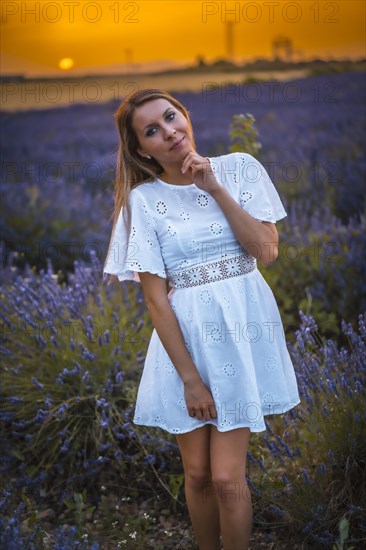 A young blonde Caucasian woman in a white dress in a cultivated lavender field in Navarra