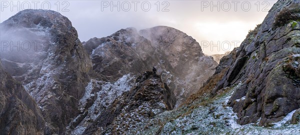 A young man on top of the mountain in the snowy winter sunset