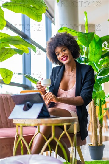 Black skinned girl with afro hair wearing a pink dress and black jacket