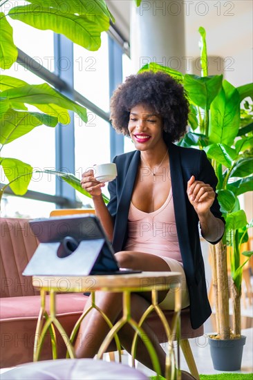 Black skinned girl with afro hair wearing a pink dress and black jacket