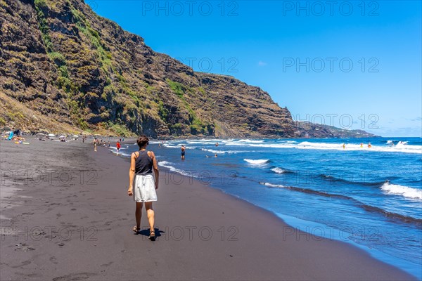 A young woman walking in summer by the sea in Playa de Nogales in the east of the Island of La Plama