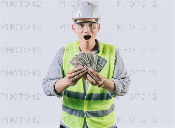 Surprised engineer in helmet holding money isolated. Amazed male engineer holding banknotes on isolated background