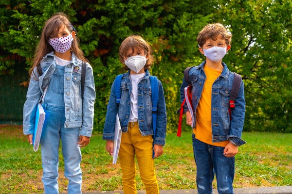 Three brothers with face masks ready to go back to school. New normality