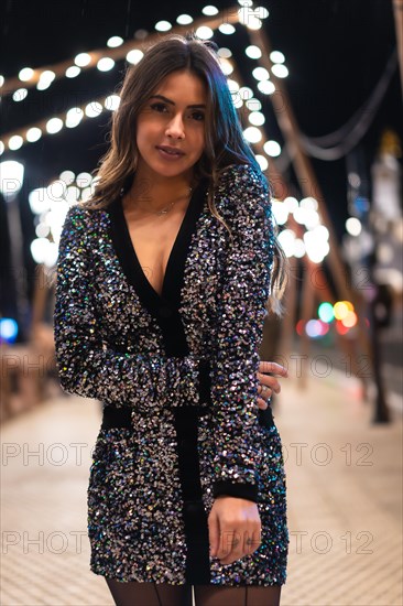 Christmas lifestyle. Portrait of a young brunette Caucasian woman in a fashionable dress with sequins