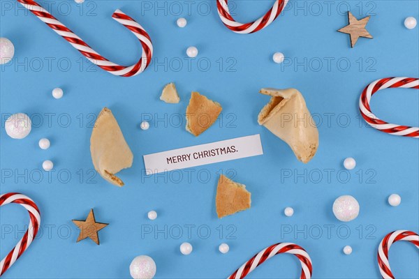 Christmas greetings with open fortune cookie and text 'Merry Christmas' on blue background with candy canes