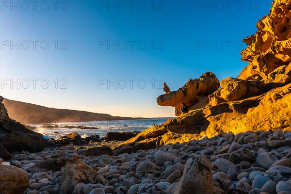 A young woman looking at the sea at sunset in the cove of stones on the mountain of Jaizkibel in the town of Pasajes near San Sebastian. Basque Country